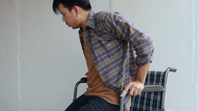 Asian man suffering from back pain on wheelchairs.