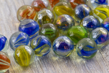 red, blue, yellow and green glass marbles on wooden background