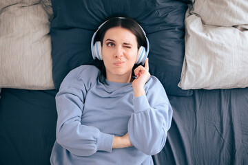 Stressed Woman Wearing Headphones Lying in Bed