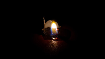 The candle flame shrank on the wood table in the darkness