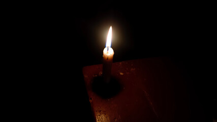 Burning candle in the dark on the wood table.