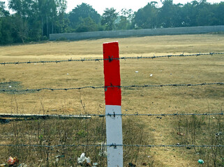 A red and white color concrete peg between a string fence