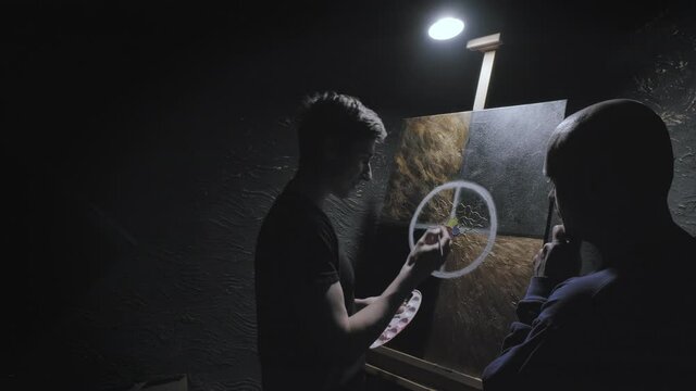 Master artist teaches man to paint. He explains in detail how to draw picture correctly. Student listens attentively, nods his head. Concept of teaching visual arts, constructive criticism and advice
