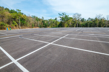 Empty space outdoor asphalt parking lot in national park. Large car park with white line paint on mountain hill in sunny day blue sky background. © pla2na