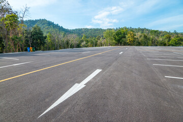 Empty space outdoor asphalt parking lot in national park. Large car park with white line paint on mountain hill in sunny day blue sky background.