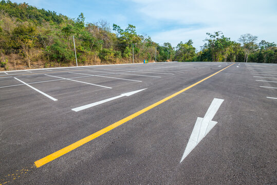 Empty space outdoor asphalt parking lot in national park. Large car park with white line paint on mountain hill in sunny day blue sky background.	