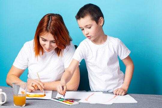 Children's creativity. mom and child son paint watercolor homework for kindergarten on blue background