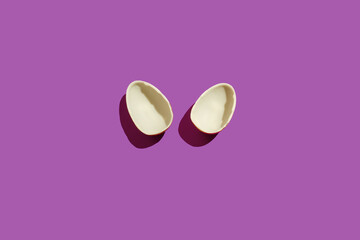 Broken chocolate eggs in the shape of bunny ears on a purple background. Easter concept