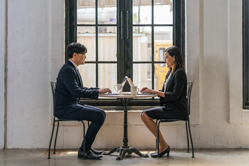 businesspeople working with laptop together by window in business workplace