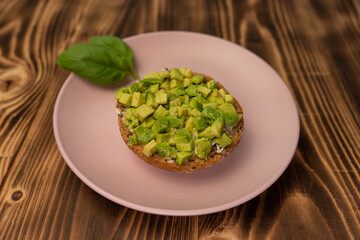 Healthy vegetarian food breakfast meal, sandwich made from avocado cubes with sunflower oil, soft cheese, cucumber on whole grain buns. Wooden board, close up