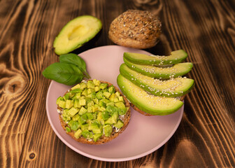 Healthy vegetarian food breakfast meal, sandwich made from avocado cubes with sunflower oil, soft cheese, cucumber on whole grain buns. Wooden board, close up