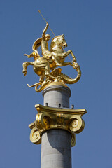 Fototapeta na wymiar Gold sculpture of St. George slaying a dragon atop a column in Freedom Square, Tbilisi, Georgia