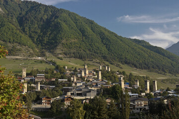 Fototapeta premium Historic tower houses amidst modern buildings on a hillside in Mestia, Svaneti region of the Caucasus, Georgia