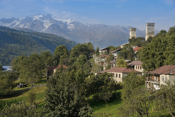 Fototapeta na wymiar Historic tower houses stand amid more modern homes on a hillside in Mestia, Svaneti region of the Caucasus Mountains, Georgia