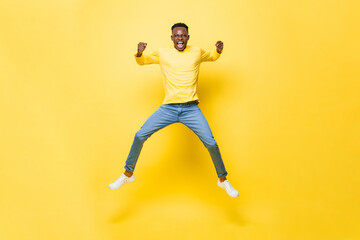 Fototapeta na wymiar Young cheerful excited African man jumping and screaming with clenching hands on isolated yellow studio background