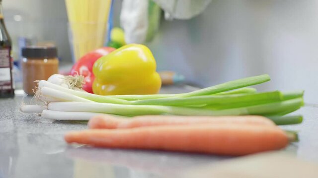 4K Delicious fresh carrots and more vegetables like peppers, garlic and leek laying in a kitchen. Close up Racking Focus with shallow depth.