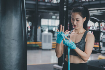 Portrait beauty sport woman wear sportwear ,boxing glove posing in boxing area under exercise with fitness equipment at gym ,she exercise for strong ,make muscle and good healthy.