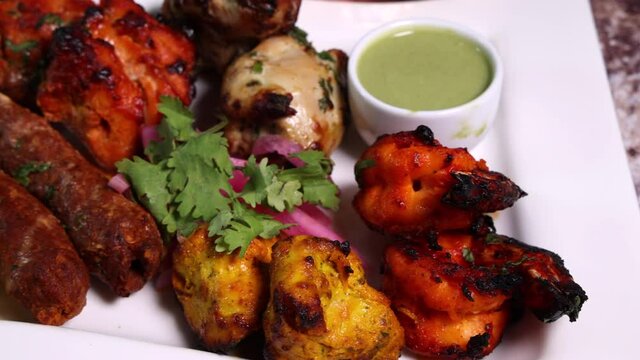 Mixed grill kebab chicken mutton beef prawn fish mint sauce lemon pickled onion bread basket chapati naan tandoori paratha dal lentil fry tadka copper pot on white dish over rustic background 