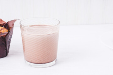 tasty muffin closeup  on a wooden board and delicious, natural cocoa drink with  chocolate and milk in a glass mug , nut muffin, homemade bakery on white  background.