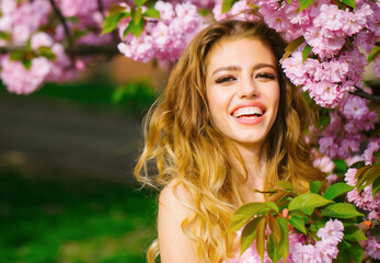 Naklejka premium Pretty woman in pink blossom park. Happy young girl with smiling face enjoy spring.