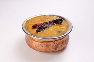 Dal lentil fry tadka with dry chilli in copper pot on white background