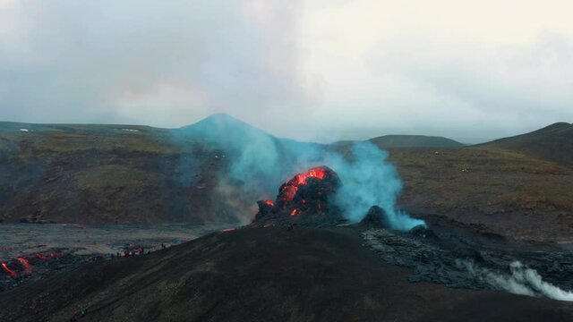 Aerial view of blue sulfur smoke rising from a erupting volcano crater, in Iceland - circling, drone shot