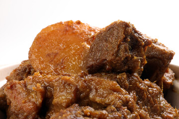 Asian style Beef bhuna dry curry with potato in ceramic bowl over white background
