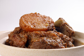 Asian style Beef bhuna dry curry with potato in ceramic bowl over white background