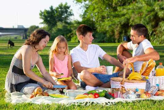 Parents with two teenagers enjoying delicious meal on the picnic. High quality photo
