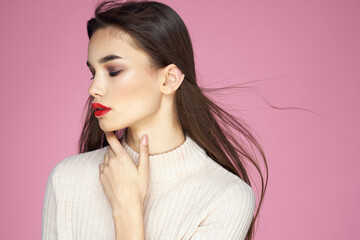 Pretty brunette in a white sweater red lips attractive look pink background