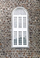 Grande fenêtre sur une tour en pierre avec cadre peint en blanc