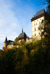 View of large Gothic Karlstejn Castle on top of hill on sunny autumn day, Czech Republic..