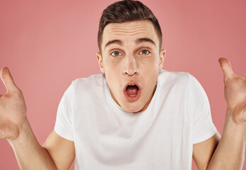 Happy man on pink background gesturing with hands in white t-shirt cropped view