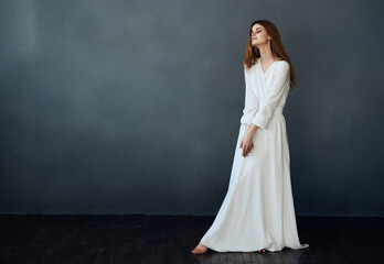 Fototapeta premium Pretty woman white dress studio performing dance gray background model