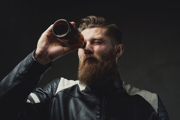 Bearded man looking throught bottle in dark background