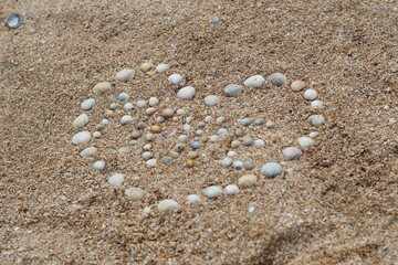 Fototapeta na wymiar Heart shape maked of sea shells on sand