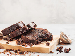 Sliced pound chocolate cake stands on white with chocolate chips and cocoa.