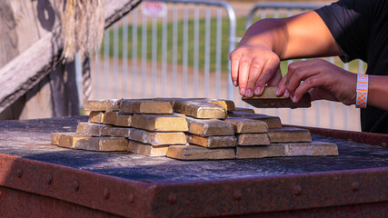 Pieces of fake gold ingots on a top of a meal rusty box. Men's hands placing one ingot on the top of a pile