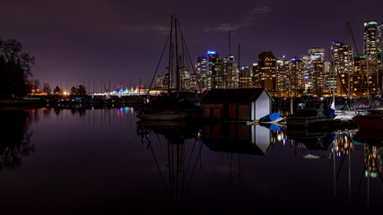 Fototapeta na wymiar Vancouver, BC \ Canada - 13 March 2019: A night long exposure photo of marina inside Burrard Inlet of Vancouver Harbor with many yachts and boats against colorfully illuminated city skyline