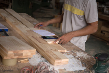 Close up hand of carpenter using smart phone to check new orders from customer 