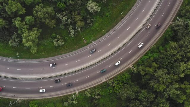Smooth traffic at the turn of the two-lane highway - Traffic of cars on the section of the highway with a smooth turn -Traffic on a stretch of curved road in a protracted turn - top view drone shot