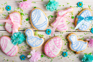 Easter frosted cookies in shape of egg chicken and rabbit on white wooden table background along with sugar sprinkles. Flat lay horizontal mockup.