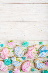 Sugar sprinkles and Easter frosted cookies in shape of egg chicken and rabbit on white wooden table background. Flat lay vertical mockup with copy space.