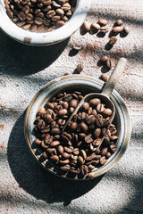 Coffee beans in a ceramic plate on a gray background.