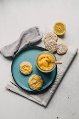 Delicious home baked almond cookies with homemade lemon curd spread on ceramic plate. Organic citrus cream and walnut biscuits. Traditional English treat. Culinary styling. Food flat lay, top view.
