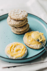 Obraz na płótnie Canvas Delicious stack of home baked almond cookies with homemade lemon curd spread and ceramic plate. Organic citrus cream and walnut biscuits. Traditional English treat. Culinary lifestyle. Selective focus