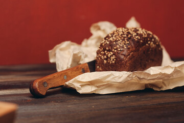 rye bread on a wooden table paper packaging sharp knife red background board
