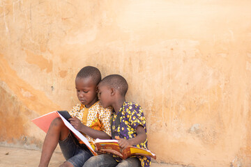 two african kids supposed to be studying playing with a phone instead