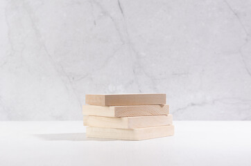 Wooden beige podium of planks on white wood table and marble wall. Showcase for cosmetic products, goods, shoes, bags, watches.