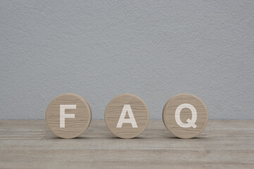 FAQ letter on wood circle shape on wooden table over white wall background, Frequently asked...